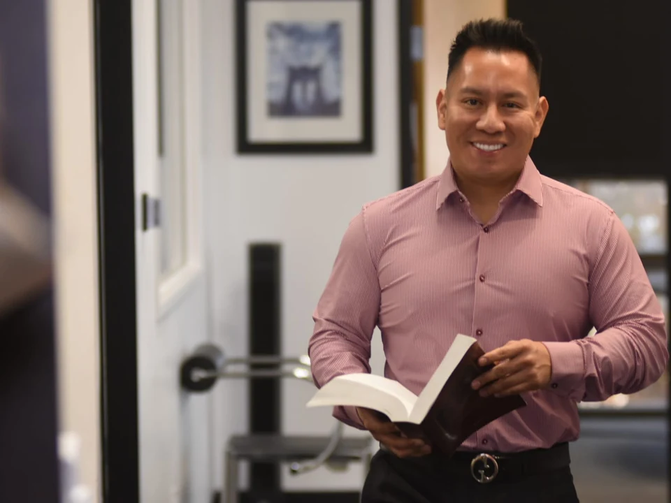 Oscar A. Ischiu in his office holding a book